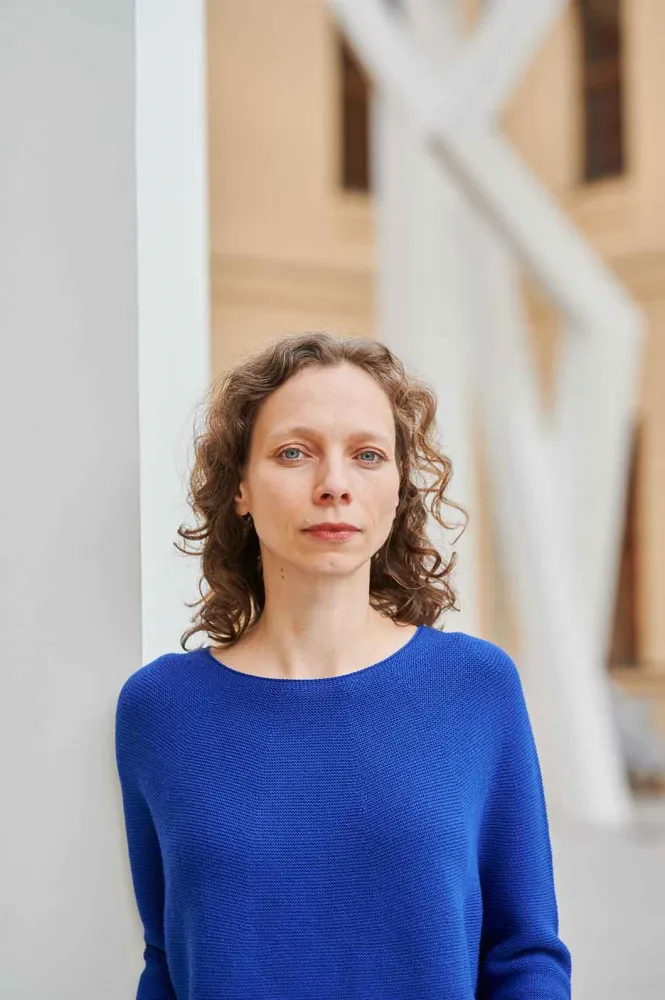 Portrait photo of a woman wearing a bright blue jumper: she looks directly into the camera.
