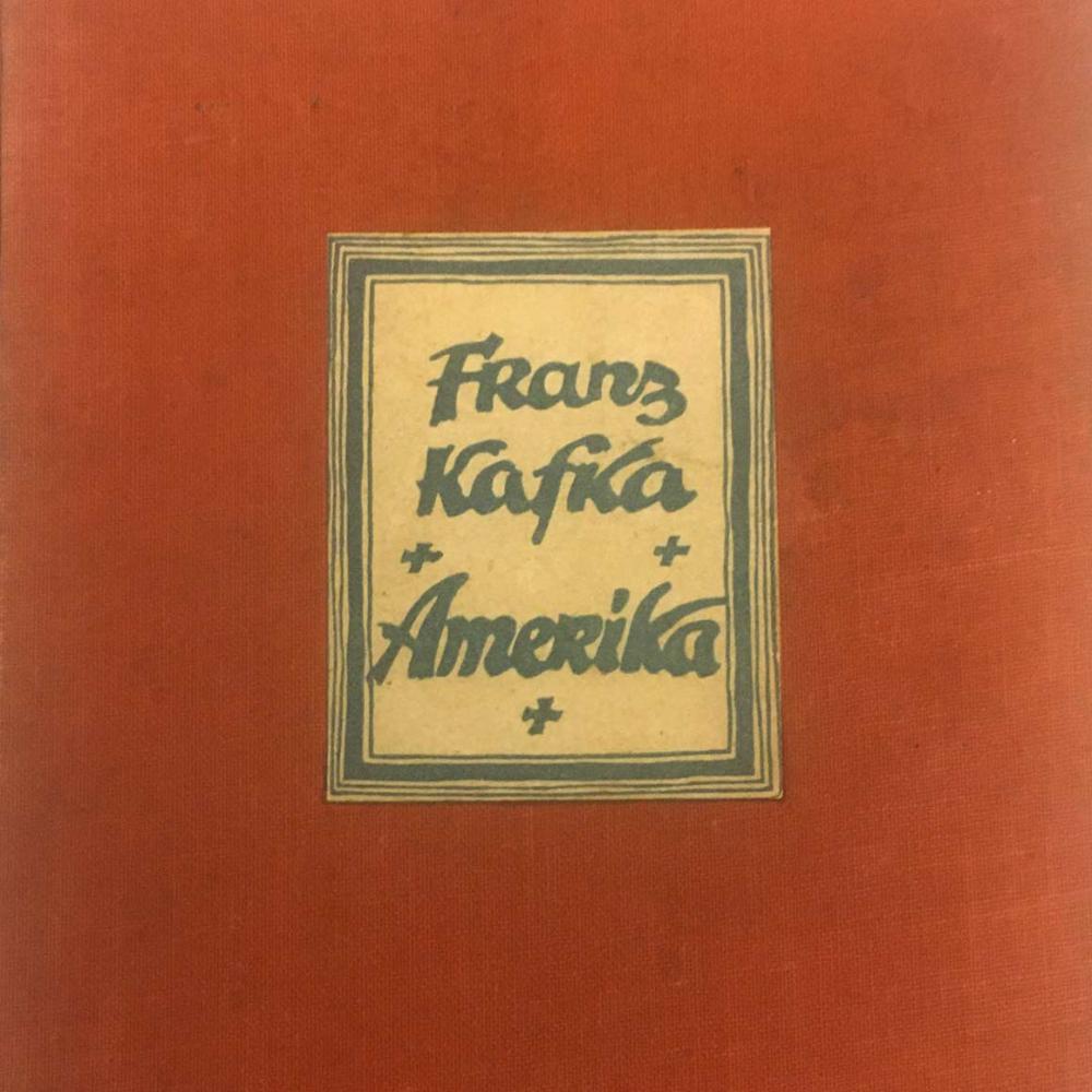 Detail from a red book cover with a glued-on, framed label with the inscription: “Franz Kafka, Amerika.”