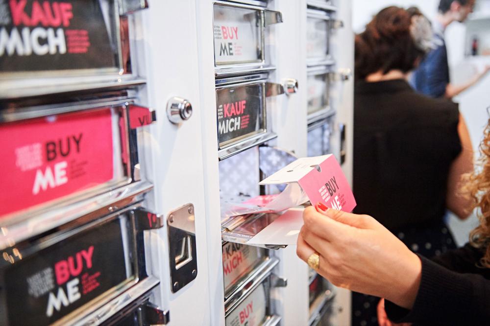 A hand opens a compartment of the art machine.