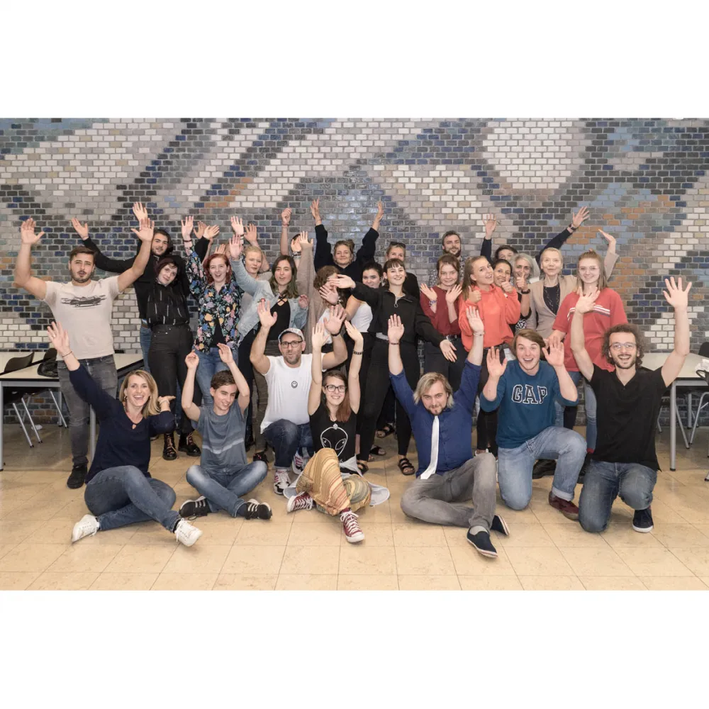 Group photograph showing around 20 teenagers raising their arms in the air