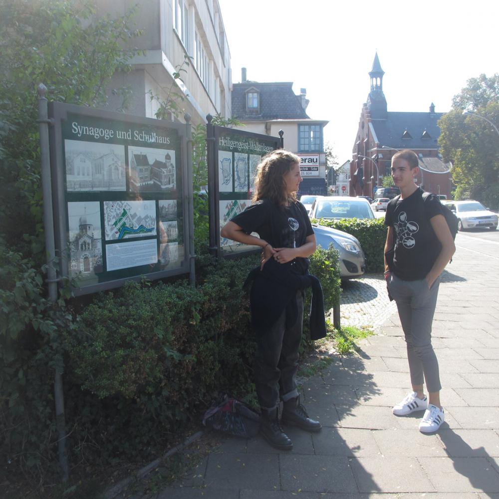 Two teenagers standing in front of the synagogue’s informational placards, in central Oldenburg