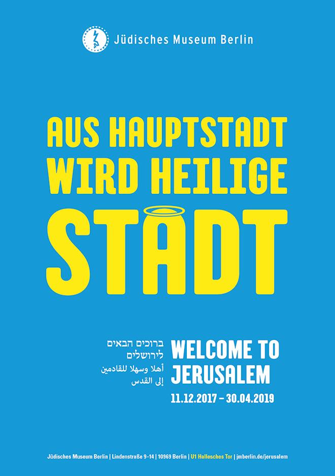 Plakat mit der Aufschrift „Aus Hauptstadt wird heilige Stadt“, wobei das letzte a einen Heiligenschein trägt