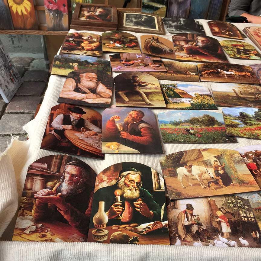 A table with paintings of "lucky jews", animals, flowers, and farm scenery