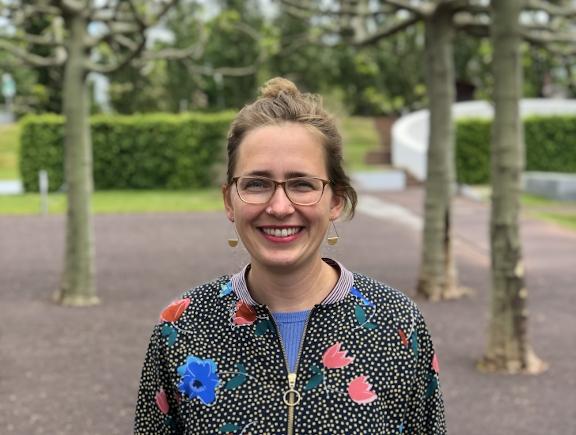 Porträt von Lisa Albrecht mit Brille und Jacke mit Blumenmuster im Museumsgarten