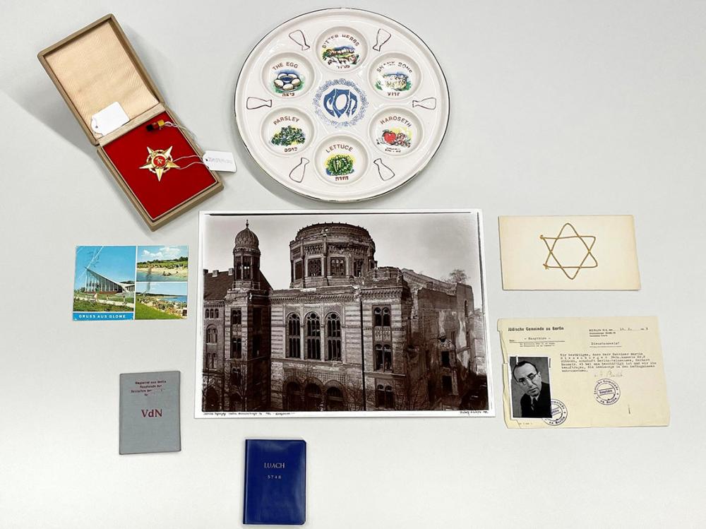 A golden five-pointed star with a hammer and sickle, a seder plate, a postcard from Glowe, a photo of the ruined synagogue in Oranienburger Straße and various identity papers