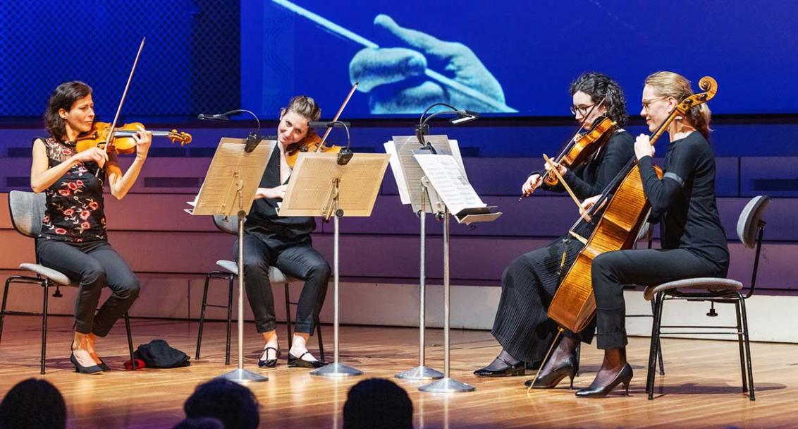 Das Bild zeigt vier Frauen, die ein Streichquartett bilden. Sie spielen Instrumente: Drei Geigen und ein Cello.