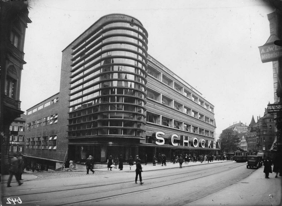 Black and white photo: A multi-storey building with a partially curved and glazed front and large letters of the Schocken department store.