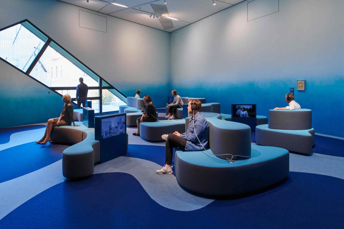 Room in shades of blue with wave-shaped seating and recessed TV screens