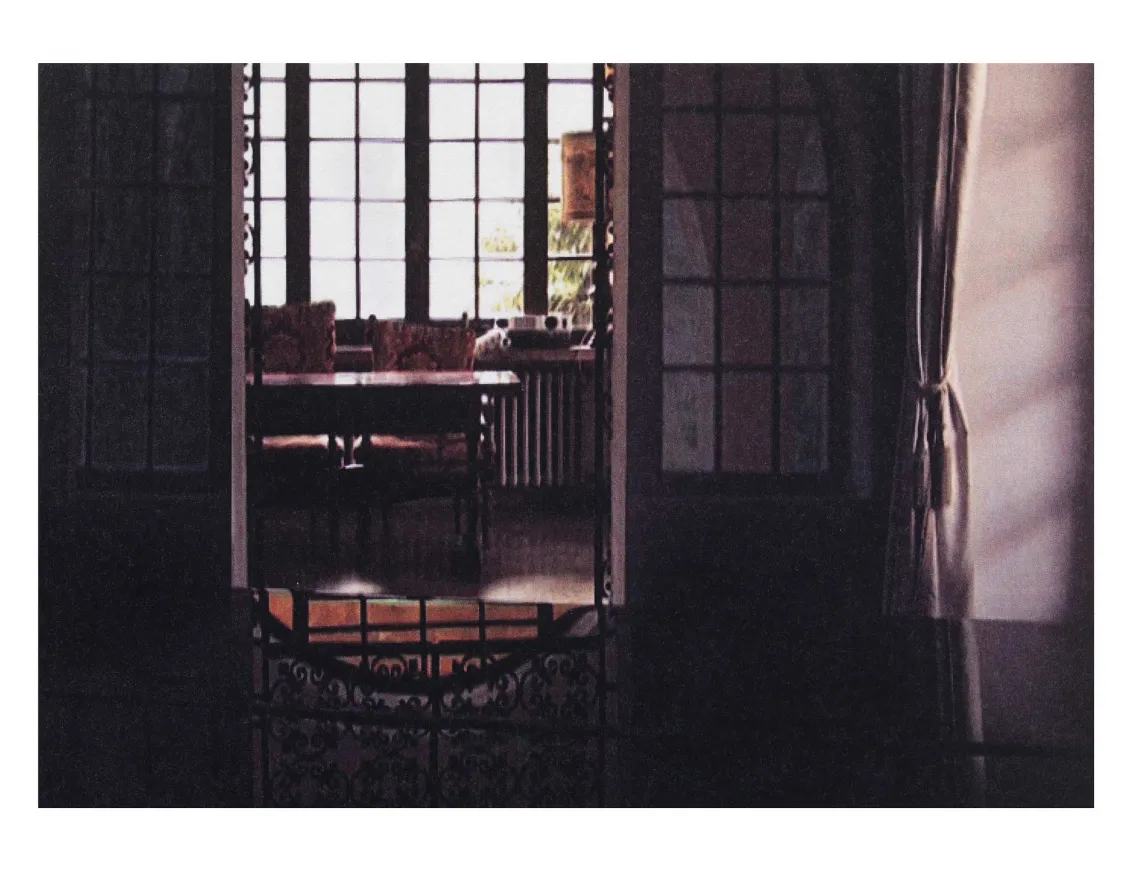 A mirror is seen in the daylight to reflect a set of chairs placed around a table