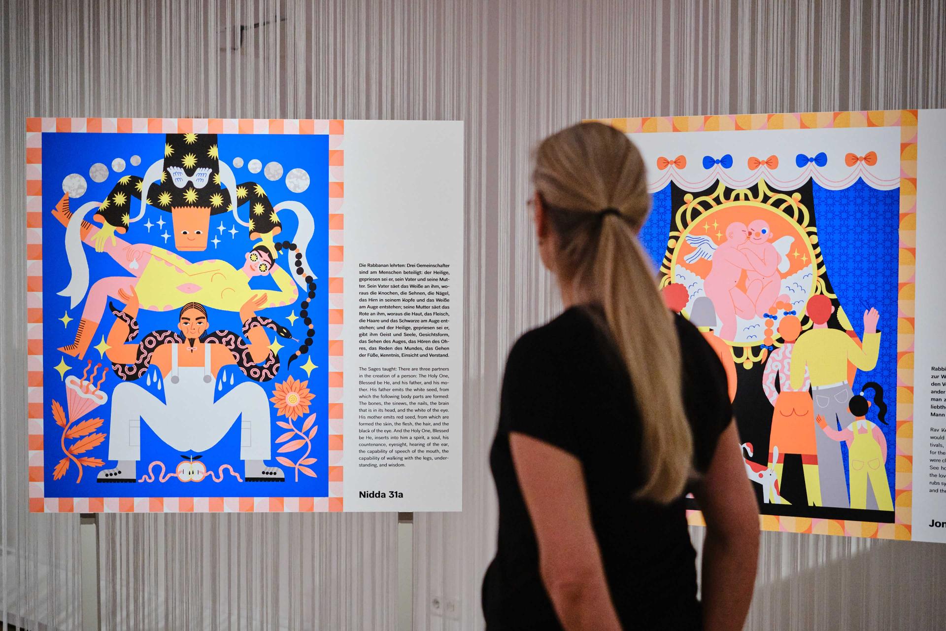 The image shows the back of a woman looking at two art works. 