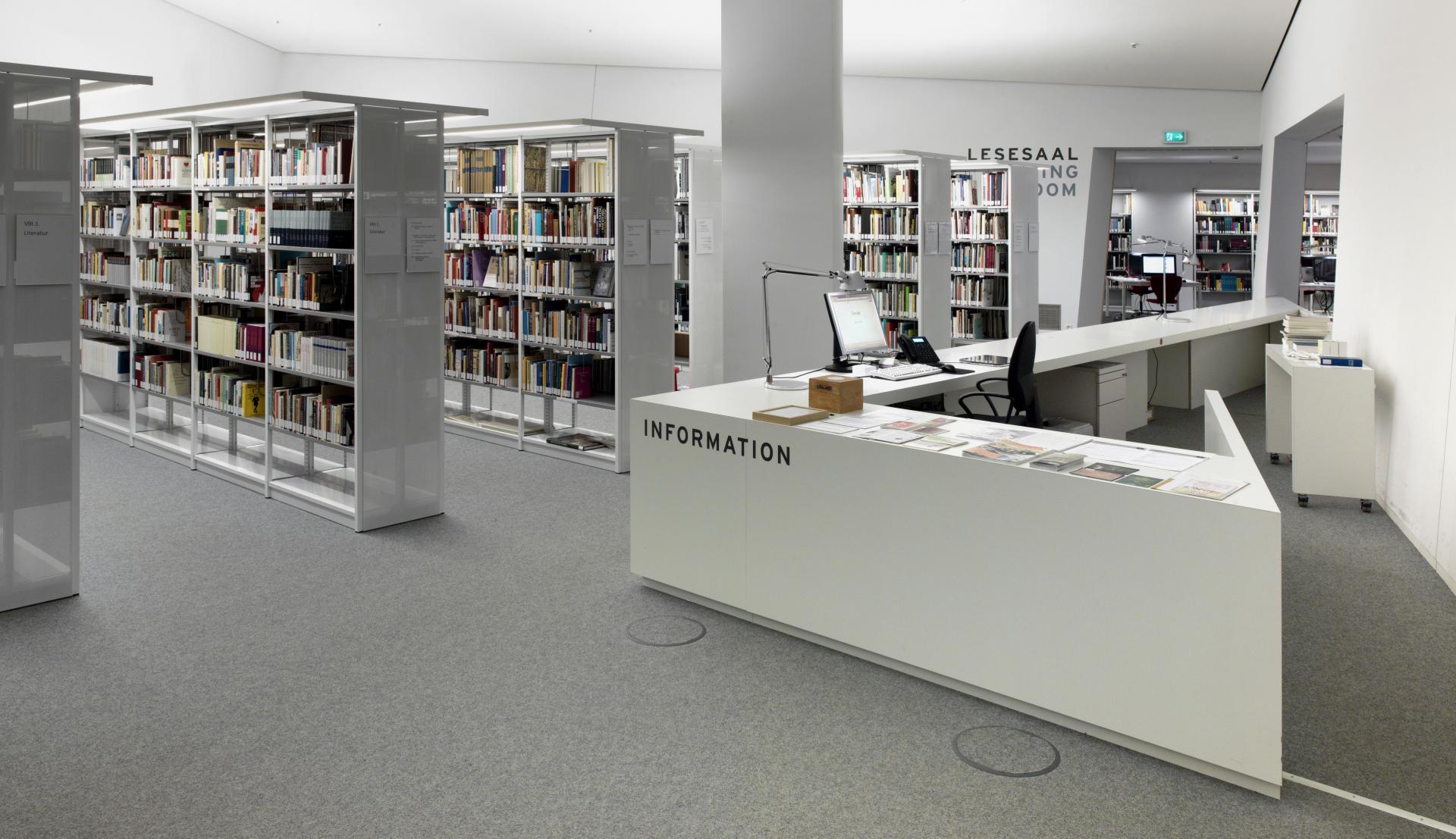 Bright space, the interior dominated by pointed geometric shapes in the style of the Libeskind museum building with bookshelves and information counter