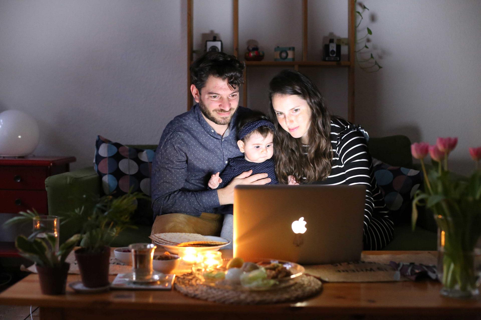 Ein Mann, ein Kind und eine Frau sitzen vor einem Laptop