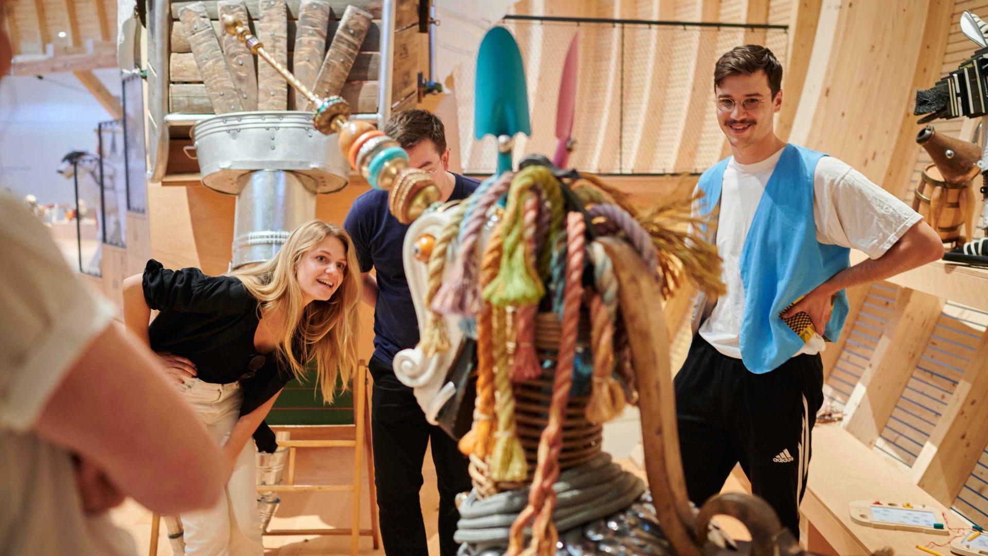 Three adults examine an animal sculpture.