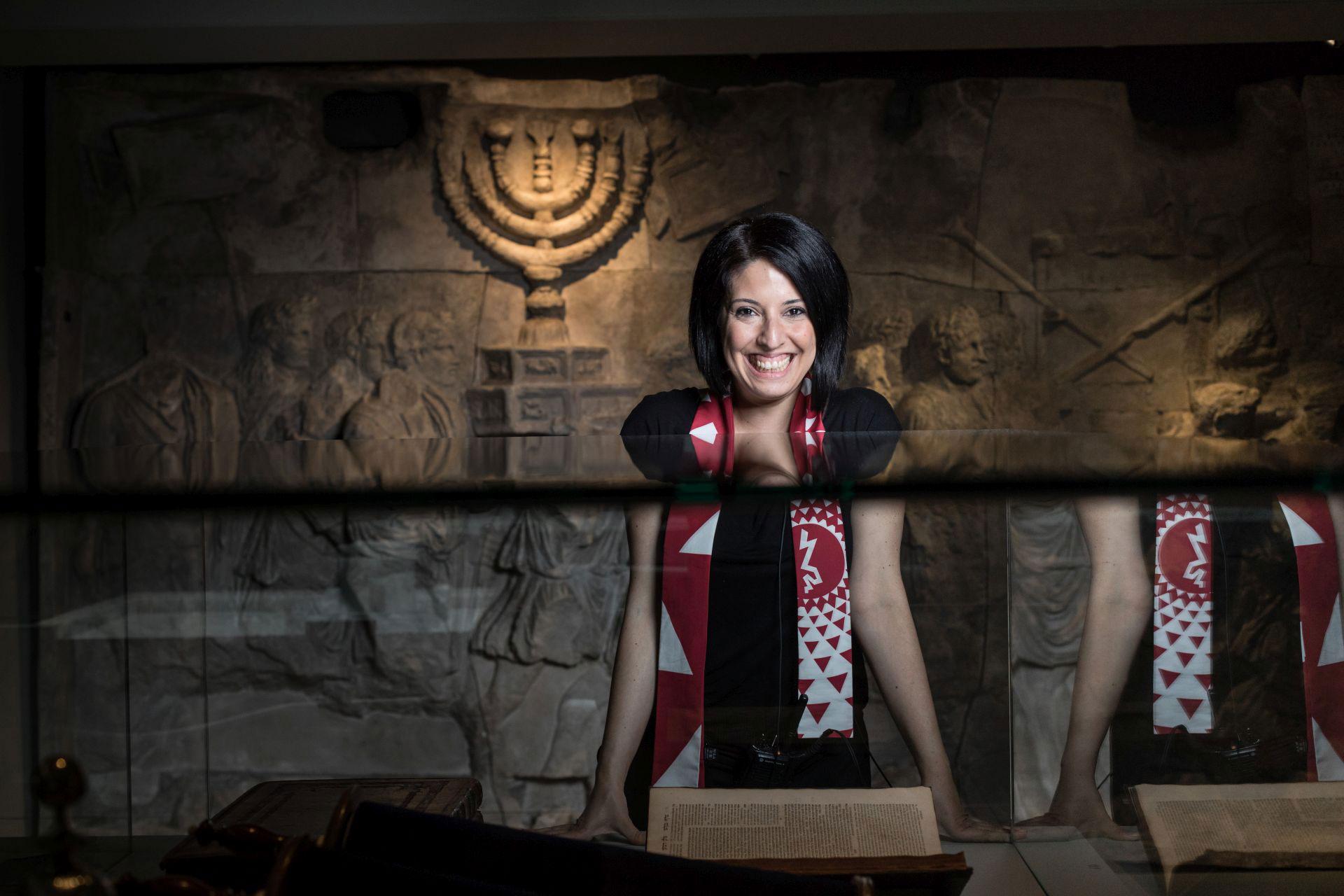 A laughing woman standing in a room of the exhibition “Welcome to Jerusalem”.