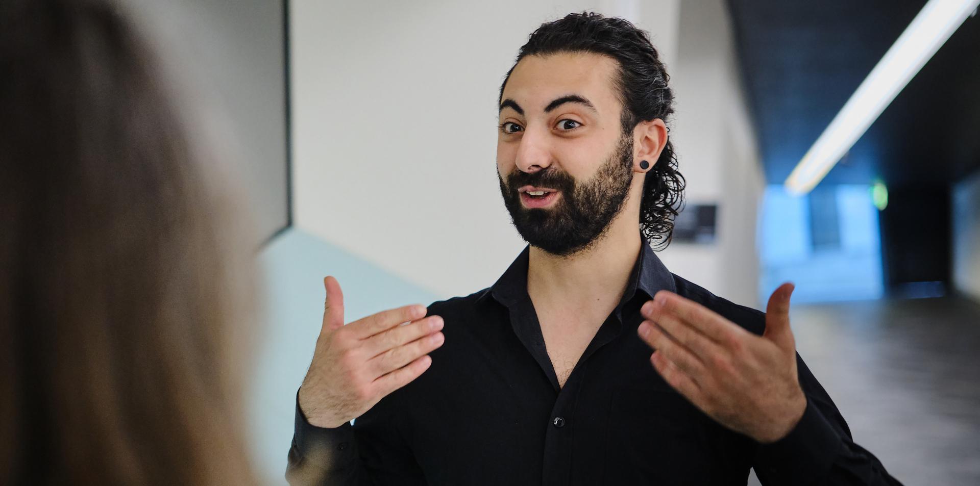 A man stands in the exhibition and gives a guided tour in sign language.