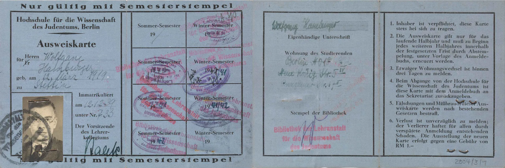 Blue paper ID card with portrait photo, filled in by hand and stamped