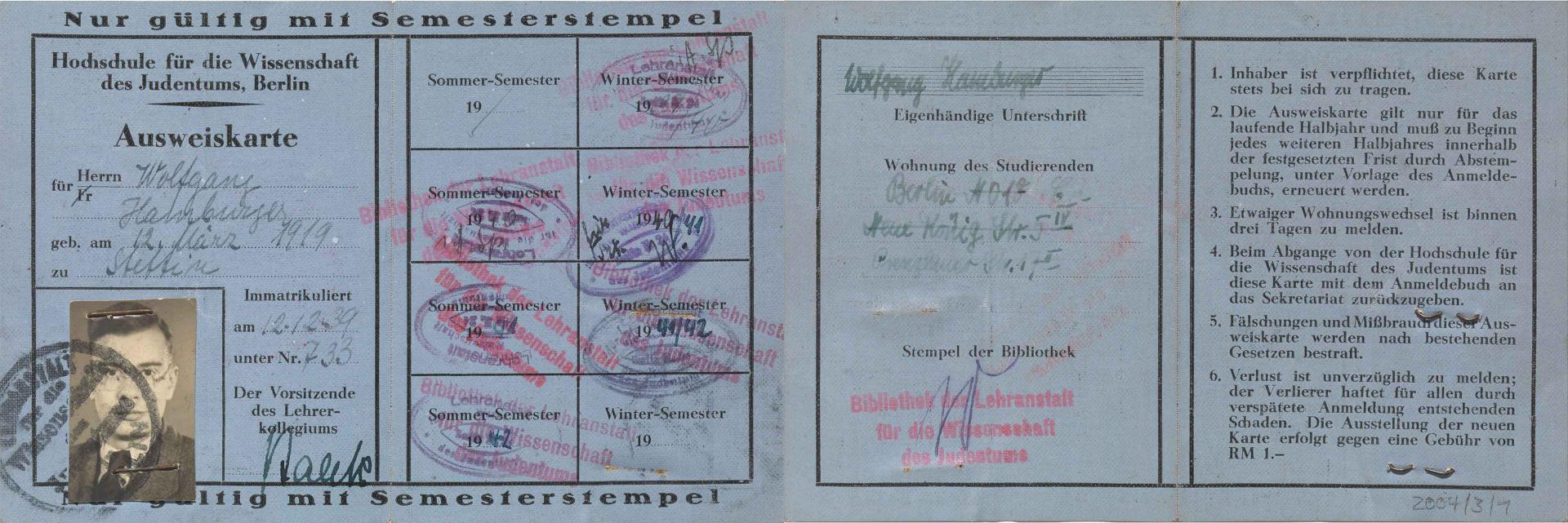 Blauer Papierausweis mit Porträtfoto, handschriftlich ausgefüllt und mit Stempeln versehen