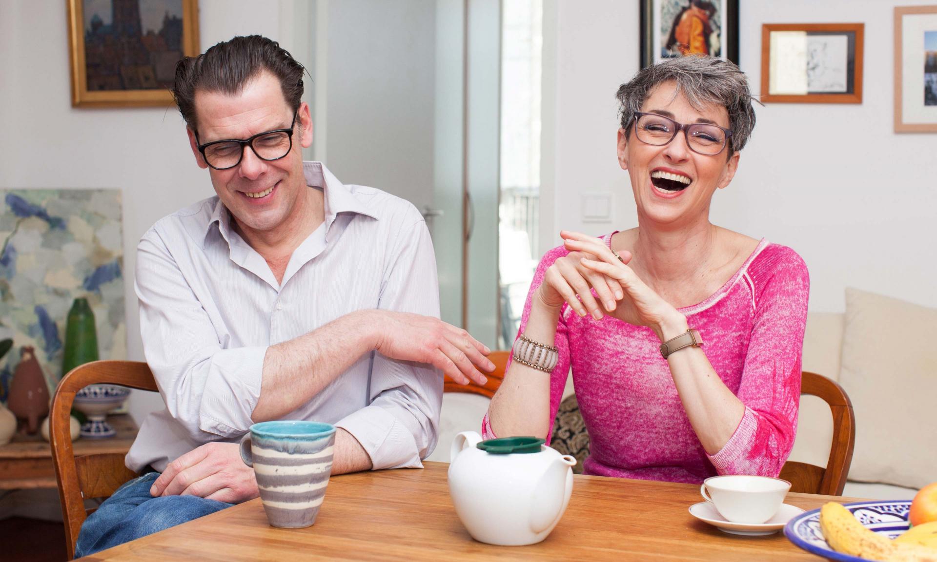 Man and woman laughing and sitting around a table