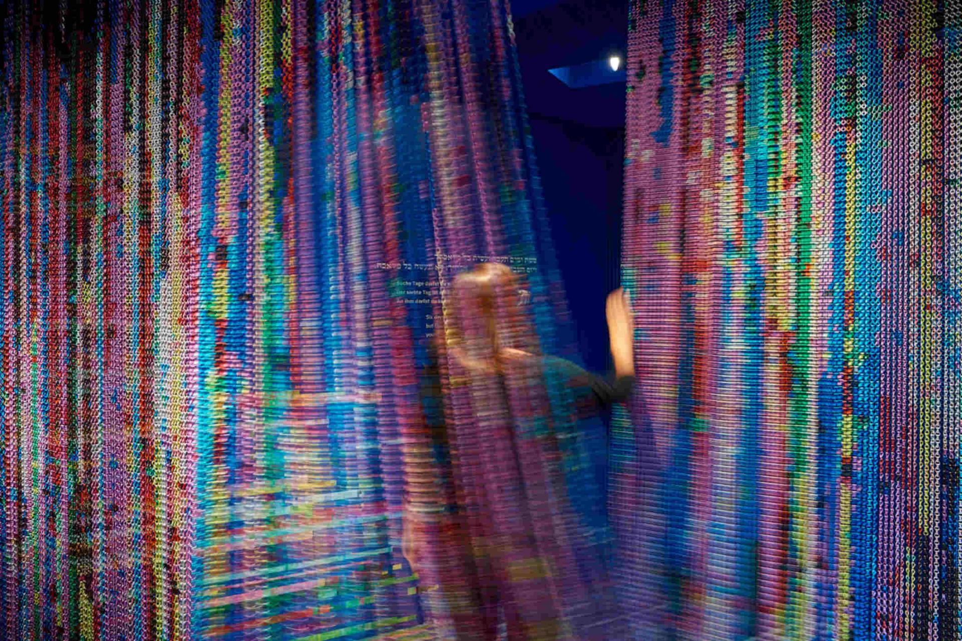 Colorful curtain in motion through which a person passes.