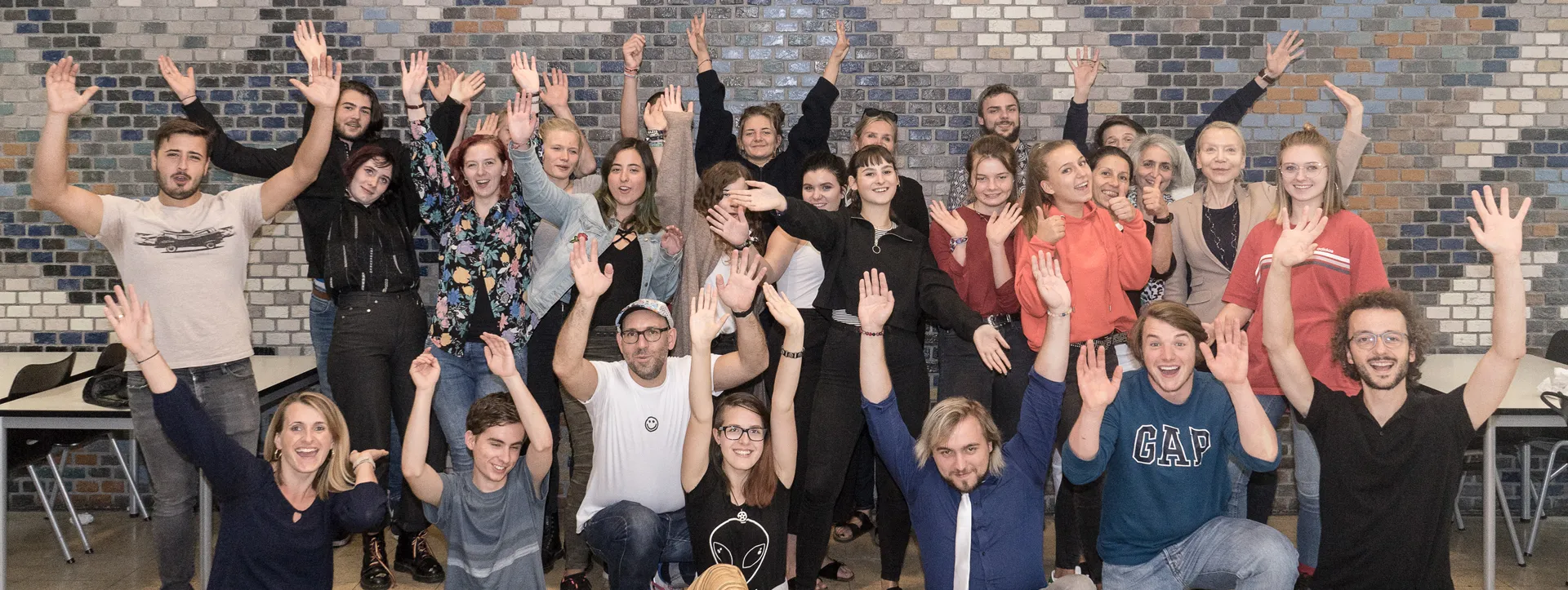 Gruppenfoto von etwa 20 Jugendlichen, die die Arme hochreißen