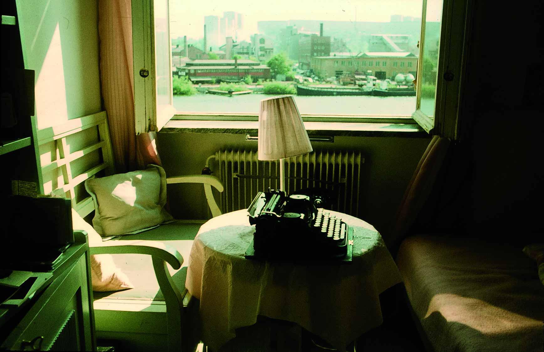 In front of the open window you can see a typewriter on a small table and a lamp with a slanted shade