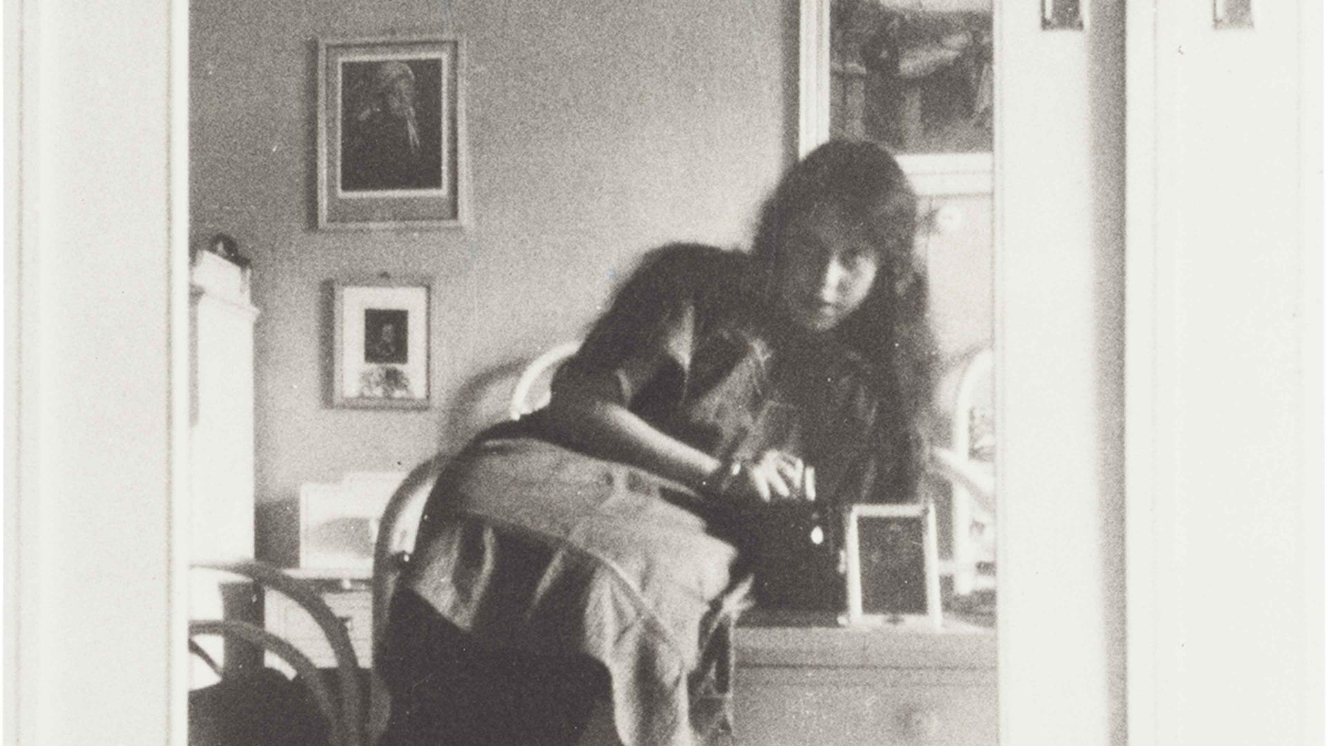 Teenage girl in a mirror attached to the door of a light cabinet