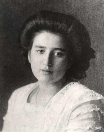 Black and white portrait photo of a young woman with voluminous, dark hair and a white blouse.