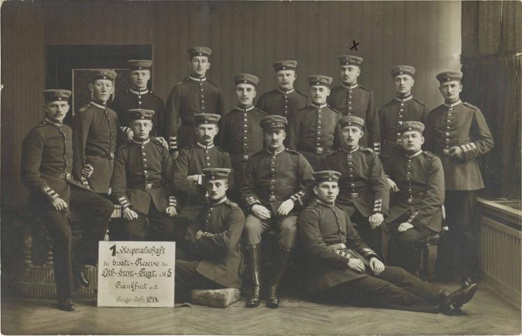 Black-and-white photograph: 17 uniformed soldiers, standing and sitting, studio photograph