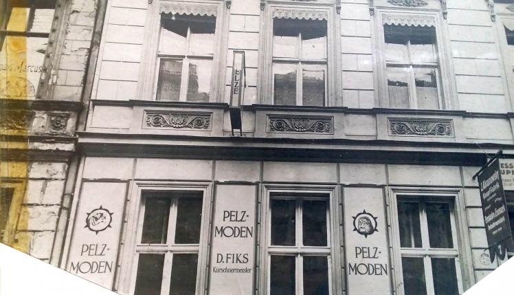 Black-and-white photograph: Façade of an apartment building with signage between the windows