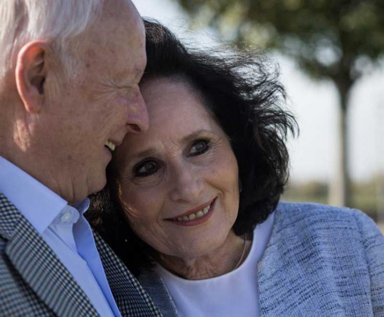 Double portrait of a couple. The upper body and head of an older man can be seen in half profile on the left of the picture, while a woman of about the same age is leaning against his shoulder, her face in three-quarter profile. Both are smiling and seem happy.