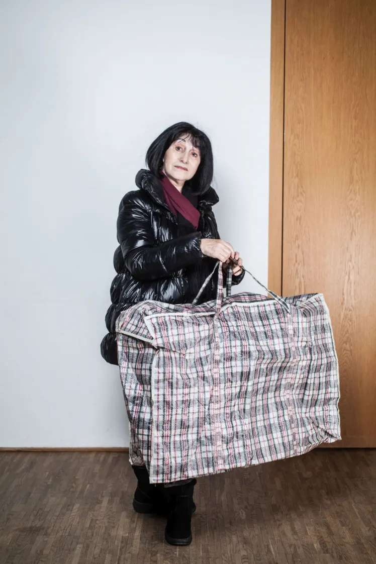 A woman in a thick winter jacket wears a huge plaid bag.