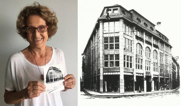 Eine Frau mit kurzen Locken und Brille hält ein Foto in die Kamera