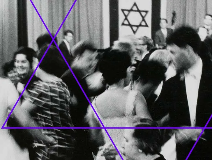 Schwarzweiß-Fotografie: Festlich gekleidete Menschen beim Tanzen, im Hintergrund ist eine mit zwei israelischen Fahnen geschmückte Bühne zu sehen, auf der eine Musikkapelle spielt.